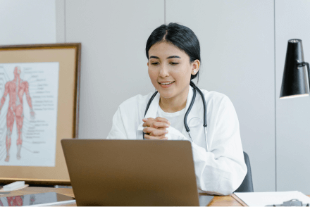 A doctor sat at her desk, using a laptop